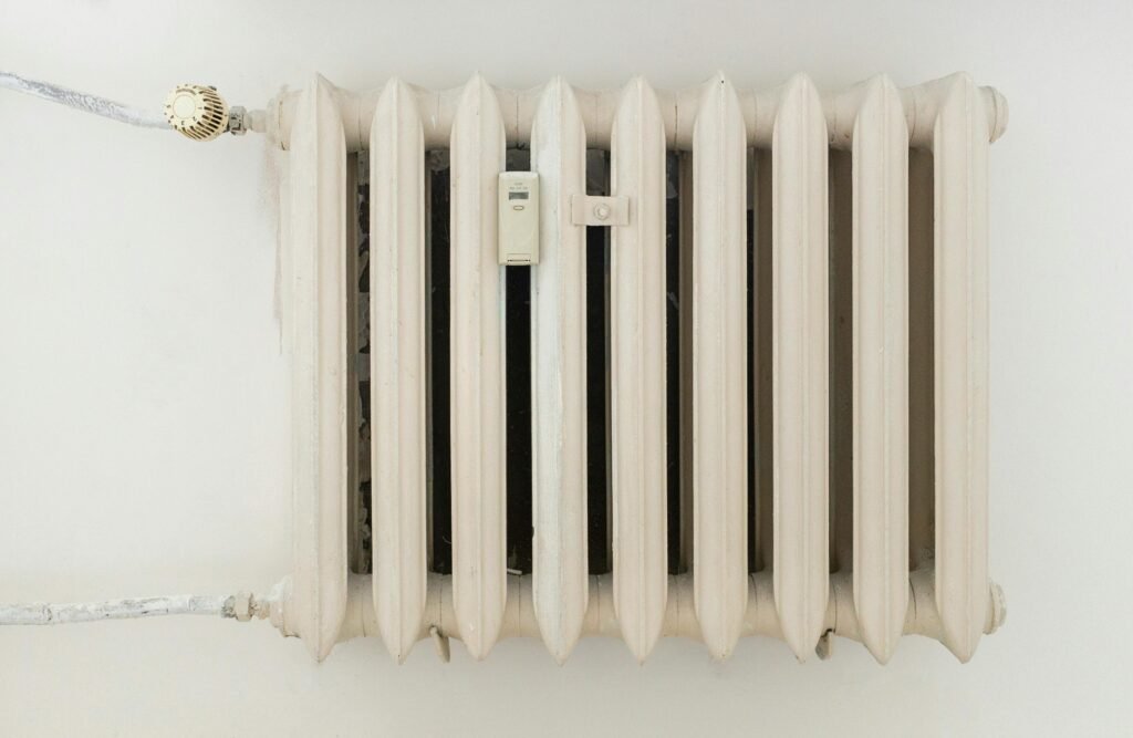 pexels photo 12034871 12034871 A classic white metal radiator on a plain wall, showcasing minimalist interior design.